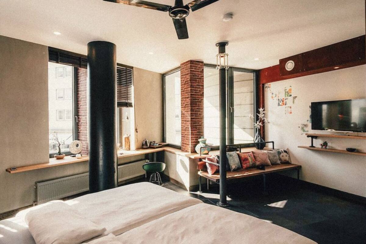 Moderni hotellihuone, jossa on suuri sänky, työpöytä, tuoli, televisio ja tiilistä tehty takka.