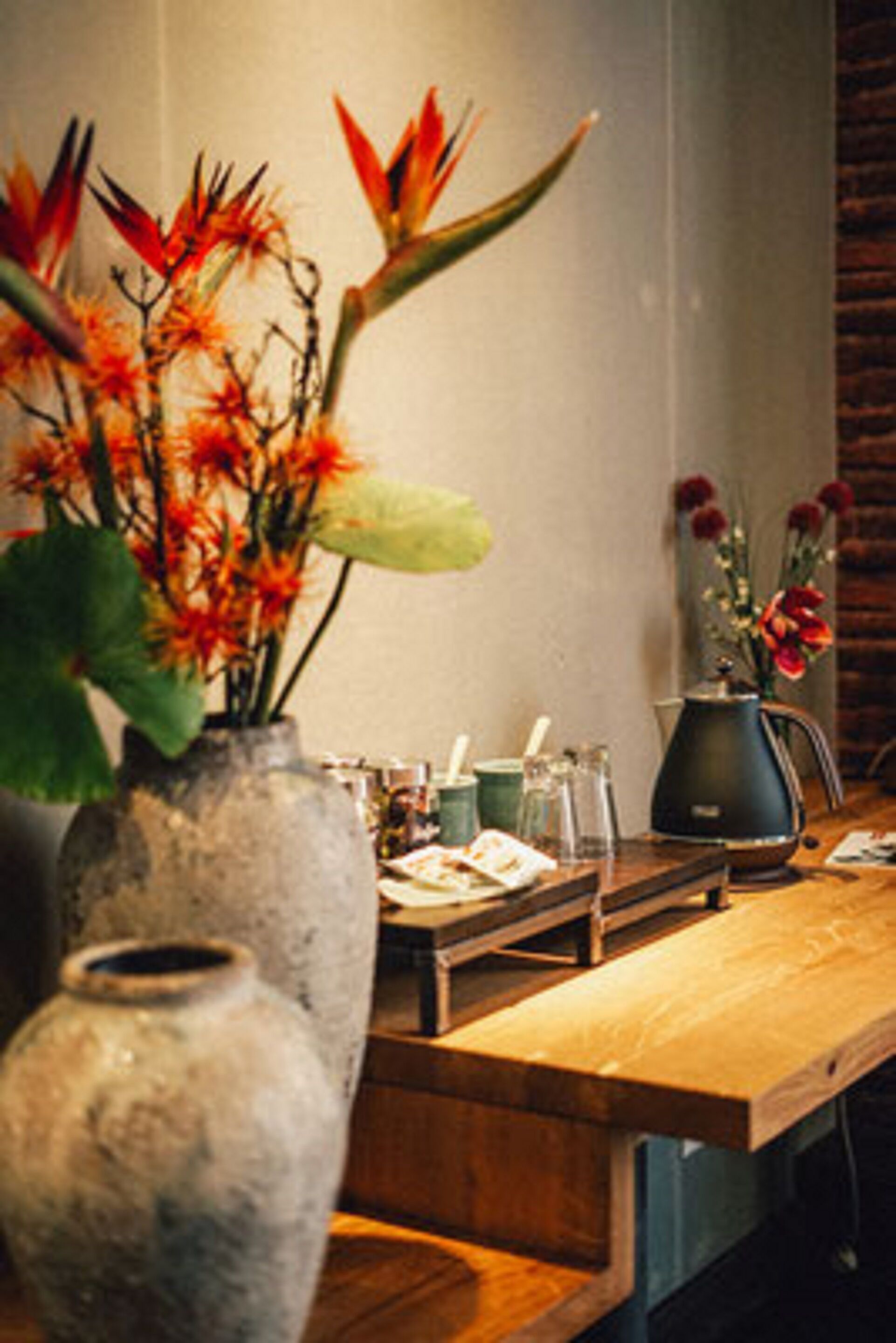 Ein Holztisch mit einer Blumenvase und einem Wasserkocher.