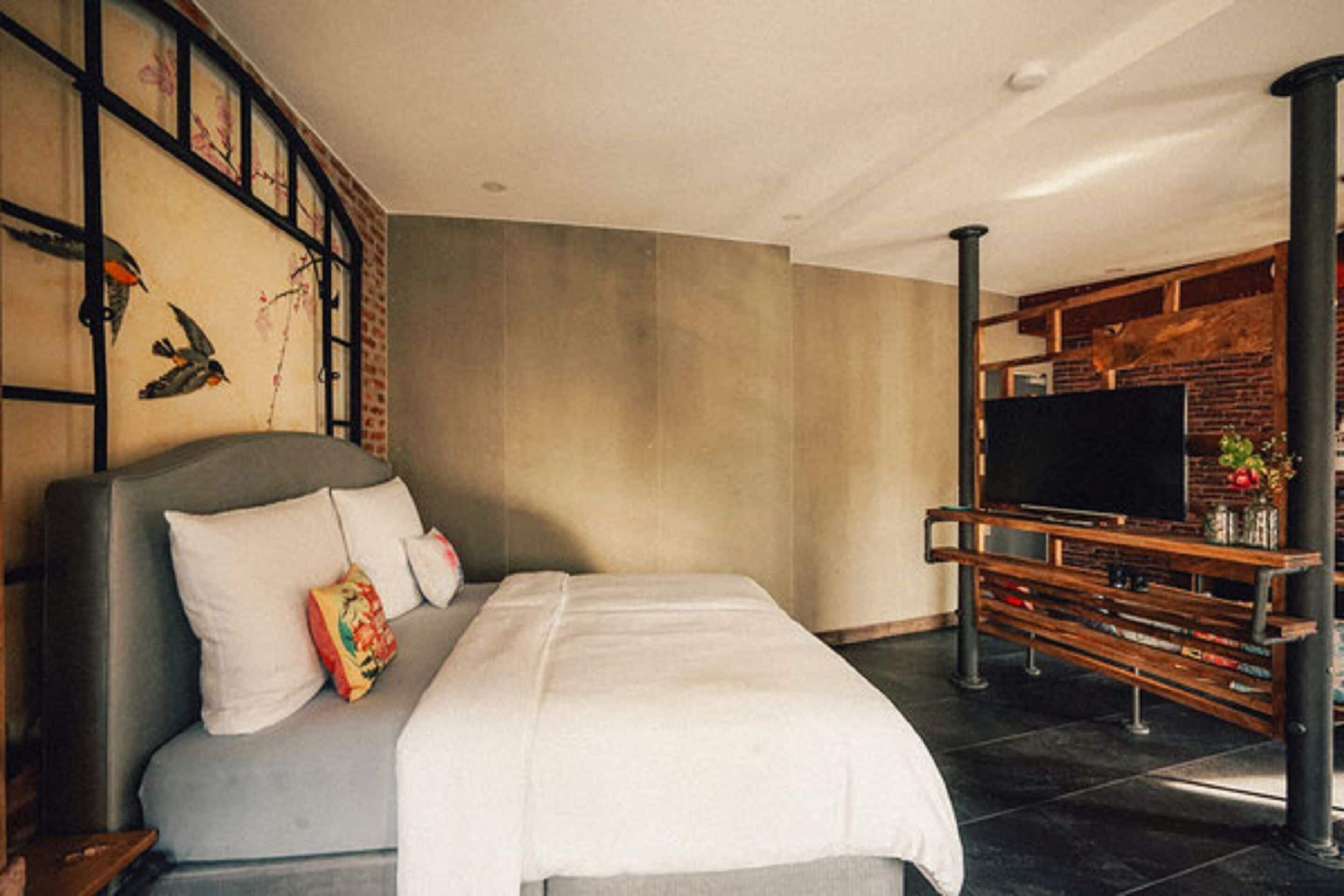 Un dormitorio moderno con una cama grande, un televisor y una pared de ladrillo.