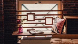 A room with a large window, a wooden table with a vase and books, and a sofa. - 36 Phô Cô Hotel & Suites (Weimar)