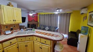 Une cuisine avec des meubles de couleur jaune, un pare-feu en carrelage et un évier encastré.