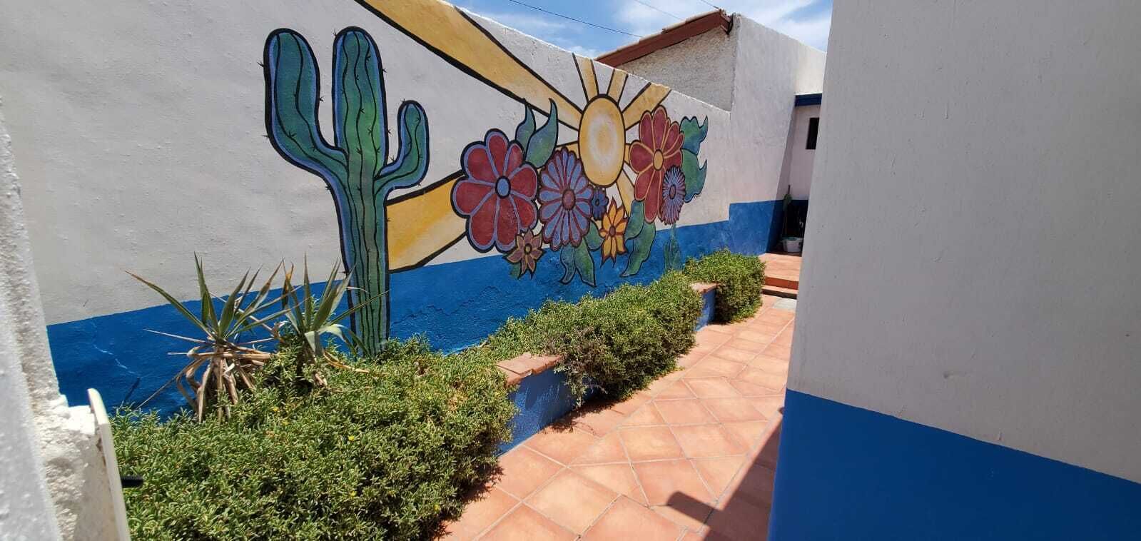 A wall with a mural of a cactus and flowers.