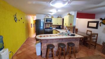 A compact kitchen with a central island, yellow walls, and a tiled backsplash.