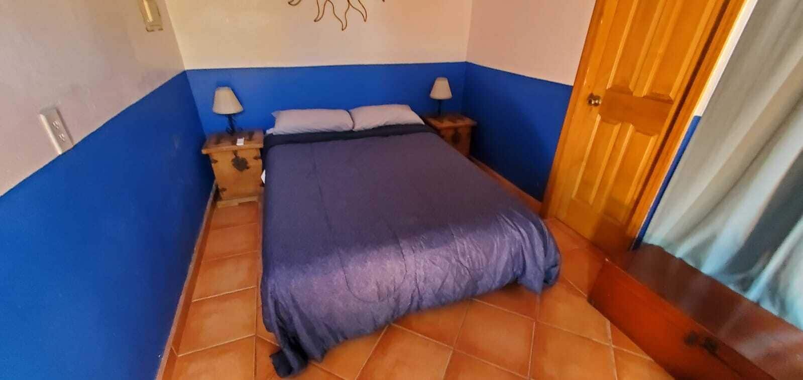 Une chambre à coucher avec un lit, des tables de chevet et une porte.