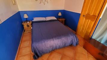 Une chambre à coucher avec un lit, des tables de chevet et une porte.