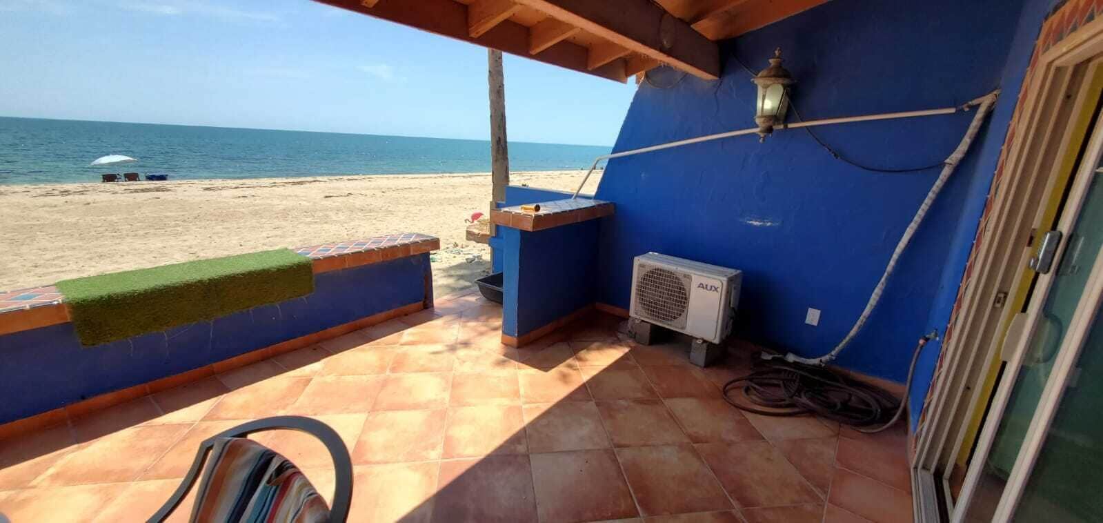 Un balcon avec vue sur la plage, un chauffe-eau et une prise de courant.