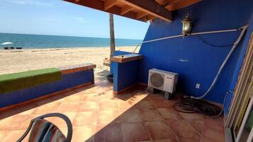Un balcon avec vue sur la plage, un chauffe-eau et une prise de courant.