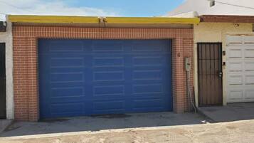 Un bâtiment doté d’un grand portail de garage bleu, d’une façade en briques et d’un toit jaune.