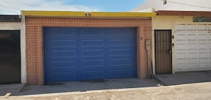 A building with a large blue garage door, a brick facade, and a yellow roof. - Mirador Beach Escape: Direct Beachfront 3-Bedroom Home (Puerto Peñasco)
