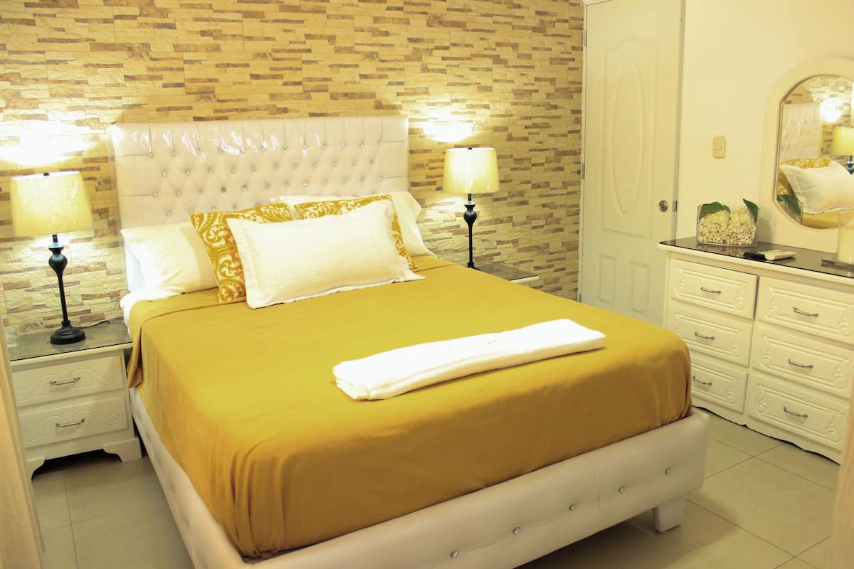 Ein Hotelzimmer mit einem Bett, zwei Nachttischen mit Lampen, einem Schminktisch und einem Spiegel.