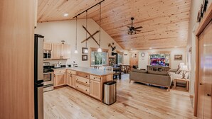 A spacious kitchen with wooden cabinets, a central island, and a dining area with a sofa and table. - 65gs - Hot Tub - Wi-fi - Pets Ok - Bbq (Deming)