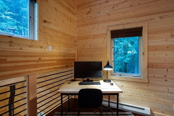 L'intérieur d'une cabane en bois, avec un bureau, un ordinateur et une chaise.