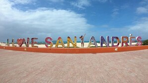 En skylt vid stranden med texten ”ÄLSKA SANTA ANDRES” i färgglada bokstäver.