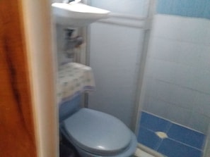 A small bathroom with a toilet, sink, and blue-tiled walls. - Room-green Sea Villa Helen Inn Located a (San Andrés)