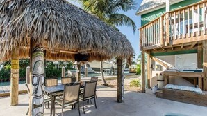 Un espace extérieur aménagé avec une toiture de chaume, une piscine et une terrasse en bois.