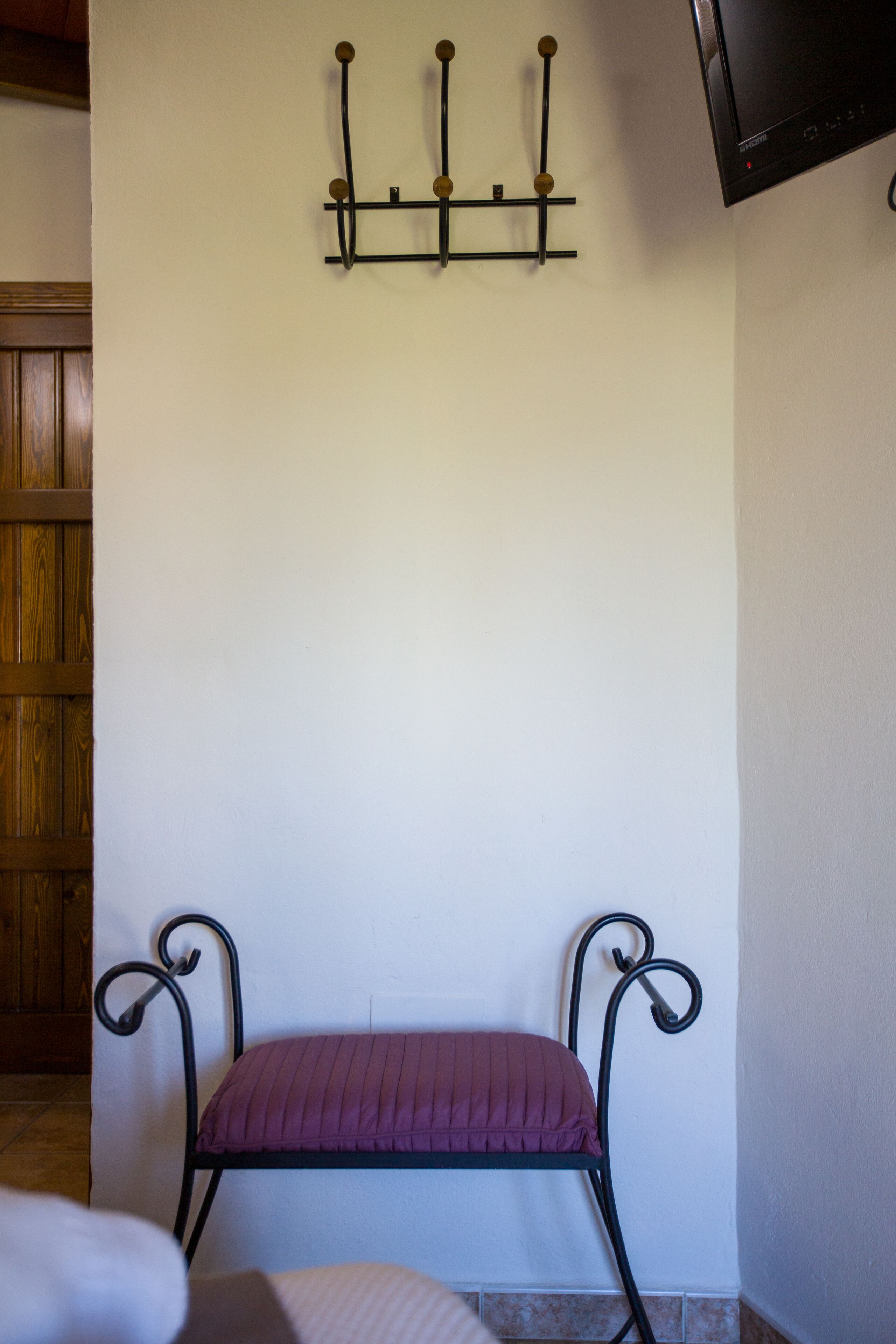 Una habitación con un banco de metal, una lámpara fijada a la pared y una puerta de madera.
