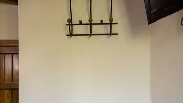 Una habitación con un banco de metal, una lámpara fijada a la pared y una puerta de madera.