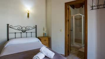 Un dormitorio con cama, mesita de noche, luz empotrada en la pared y zona de ducha.