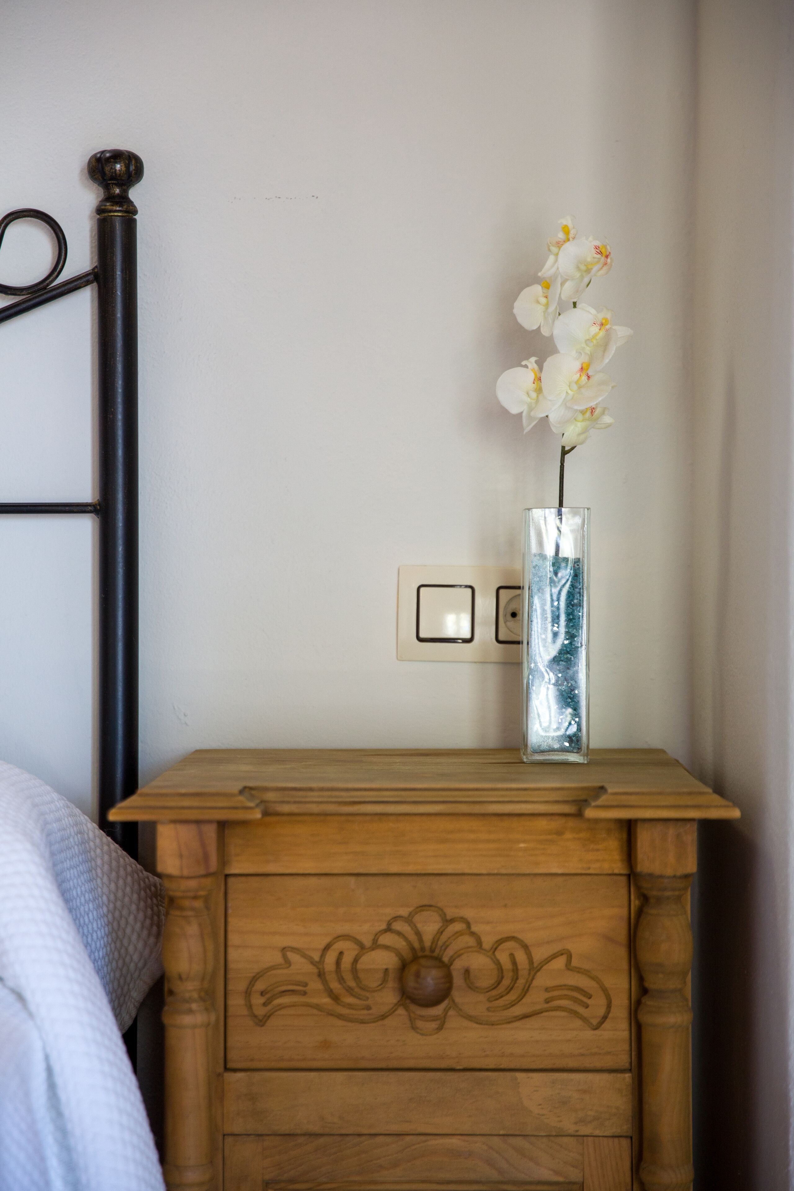 A wooden nightstand with a vase of white flowers.