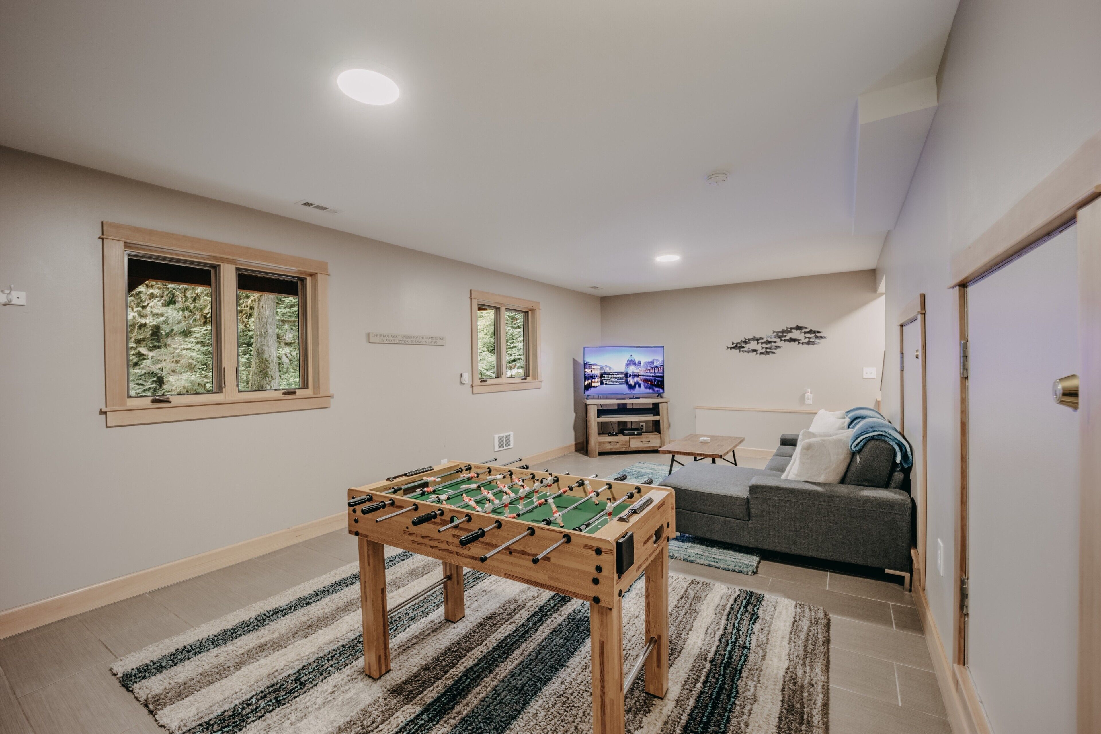 A spacious room with a foosball table, a television, and a sofa.