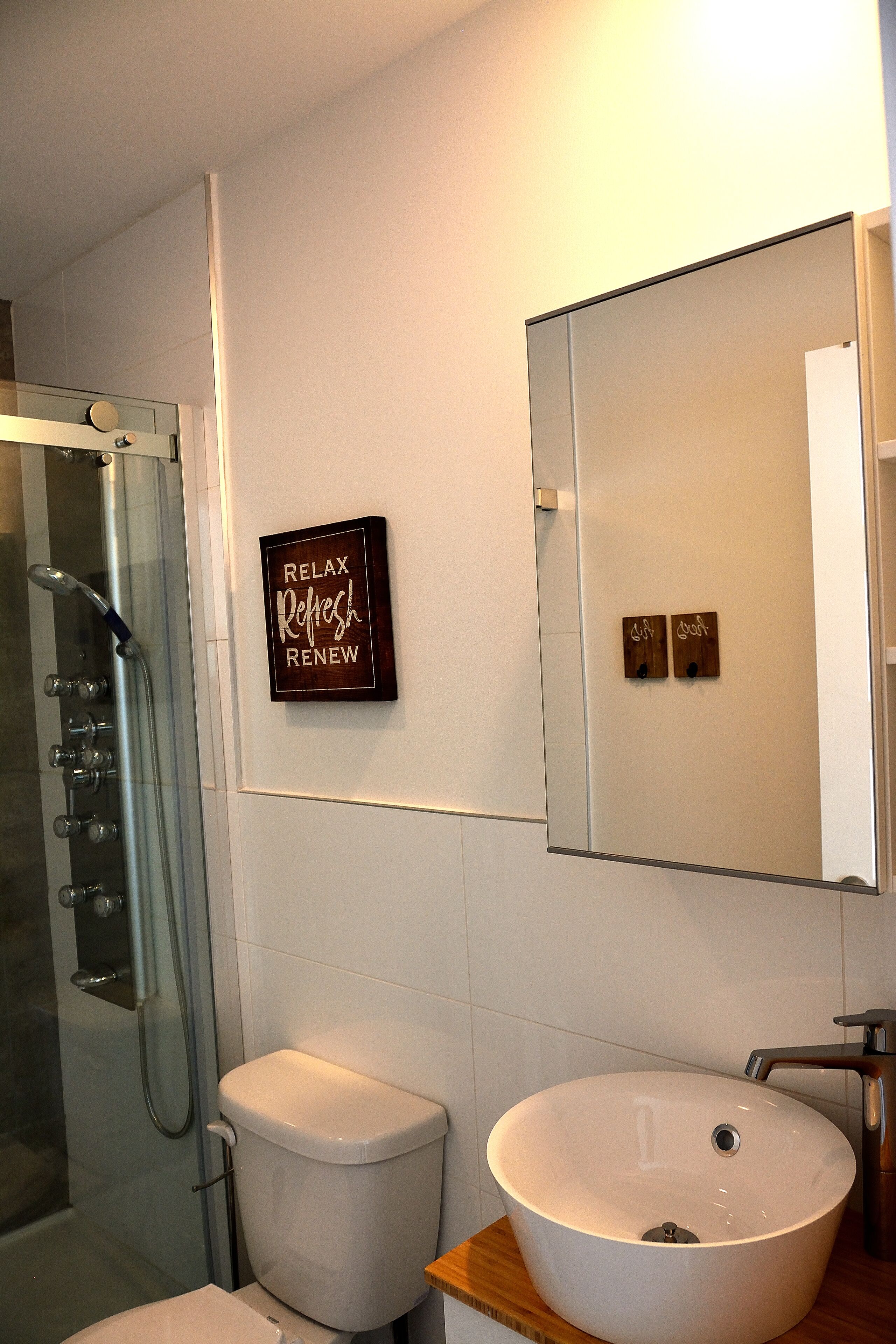 A bathroom with a glass-enclosed shower, a white toilet, and a large vessel sink.