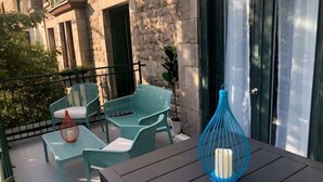 A balcony with green wicker furniture, a blue candle holder, and a stone building in the background. - Best Spot in Town! Sunny Terrace - 3 bedrooms w/ private bathrooms - Fast WI-FI  (Montreal)