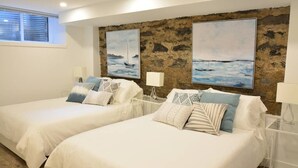 A bedroom with two beds, a stone wall, and two paintings. - FALL & WINTER SPECIAL! Huge Ground Floor apt with Courtyard - 5 bed + 6 bath (Montréal)
