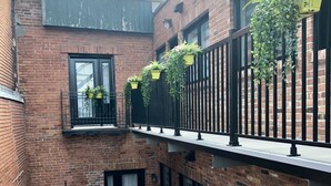A multi-story brick building with balconies, large windows, and hanging planters. - FALL & WINTER SPECIAL! Huge Ground Floor apt with Courtyard - 5 bed + 6 bath (Montréal)