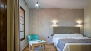 A hotel room with a bed, a chair, a small table, and a nightstand. - Hostal Don Joaquin Alora (Pizarra)