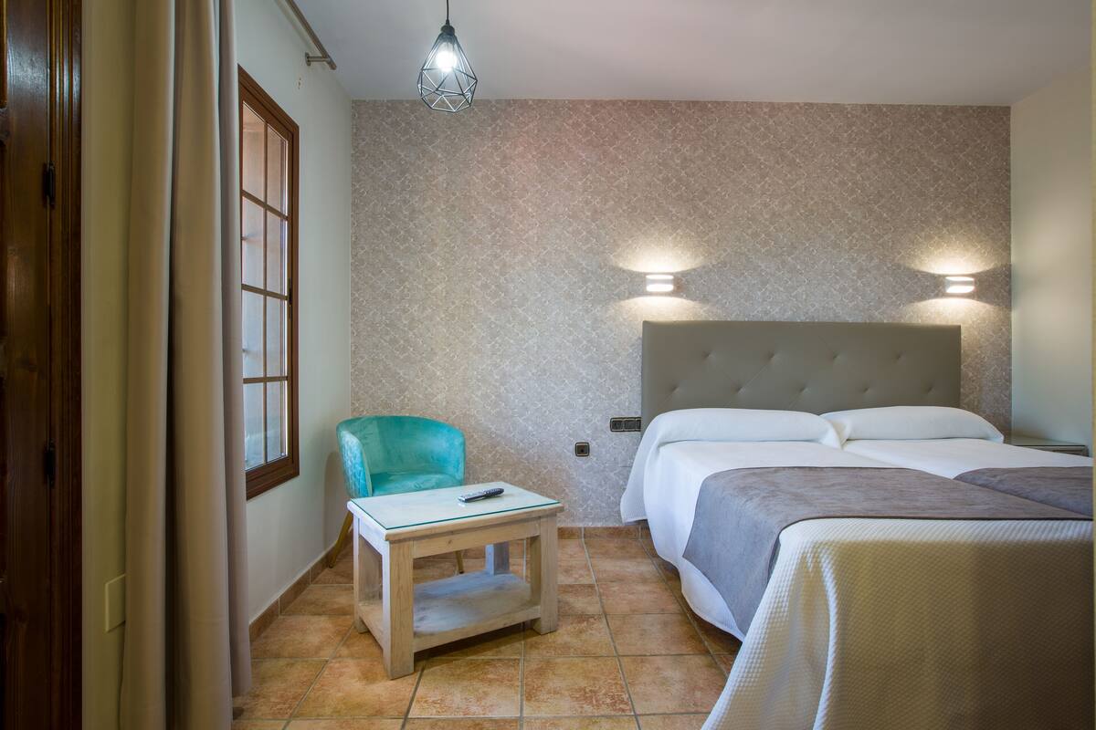 Ein Hotelzimmer mit einem Bett, einem Sessel, einem kleinen Tisch und einem Nachttisch.