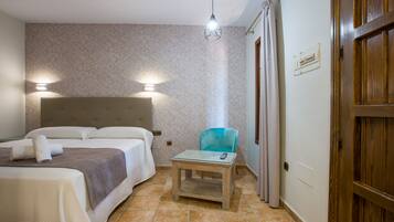 Habitación de hotel con una cama, una mesita, una silla, una mesita de noche y una puerta de madera.