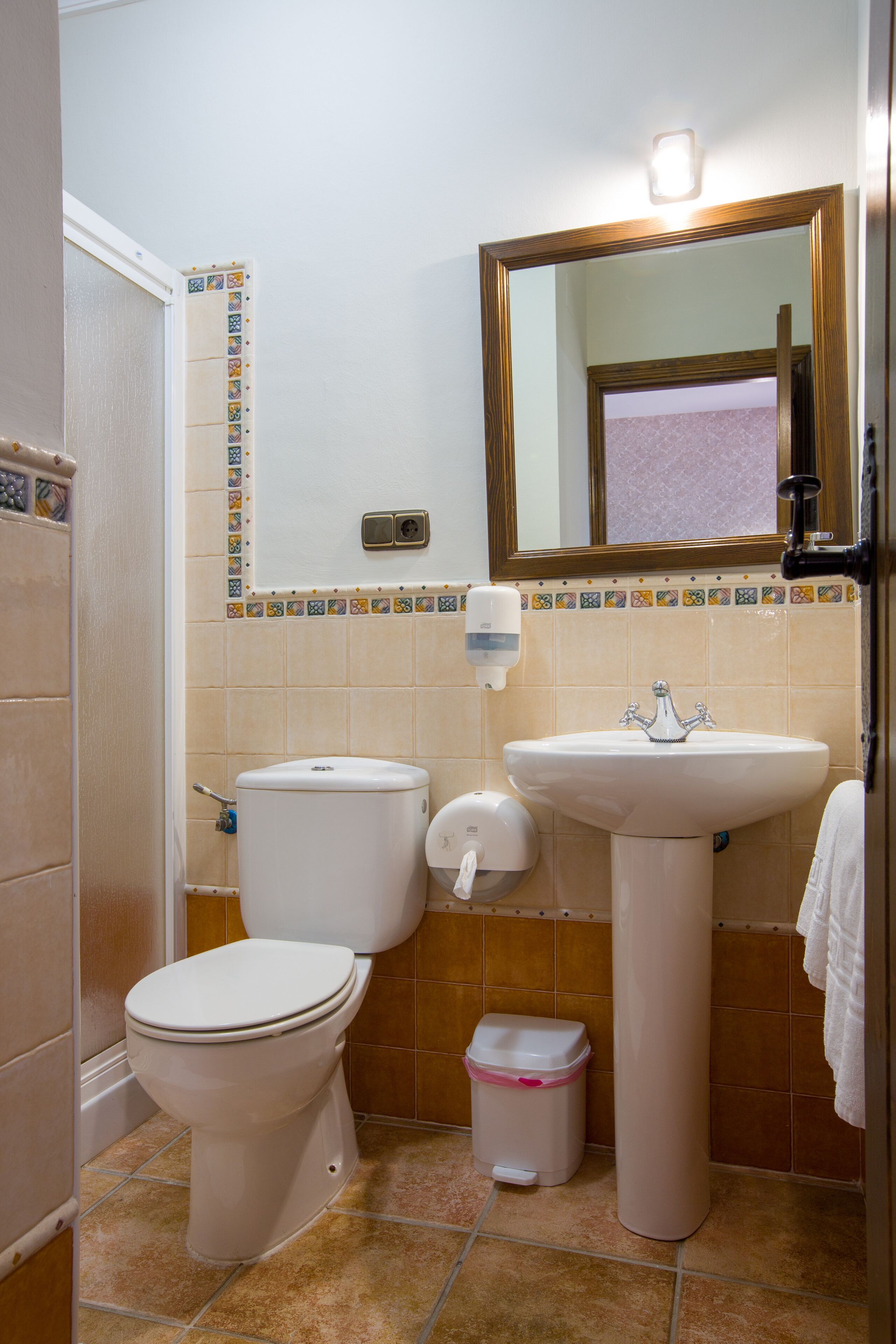 Een badkamer met twee toiletten, een wastafel, een spiegel en een prullenbak.