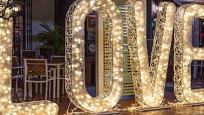 Illuminated letters spelling "LOVE" in a public outdoor area with seating and a building in the background. - Hostal Don Joaquin Alora (Pizarra)