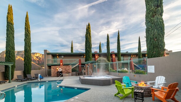A pool area with a hot tub, outdoor seating, and tall trees.