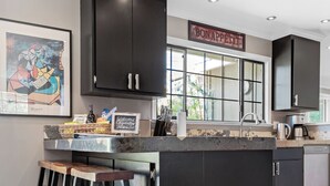 Una cucina moderna con mobili scuri, un'area bar con sgabelli, una finestra vista panoramica e un cartello di benvenuto.