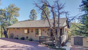 A rustic cabin with a wooden exterior, a front porch, and a small attached shed.