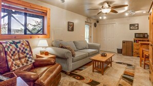 A cozy living room with a leather couch, a grey sofa, a wooden coffee table, and a patterned rug.