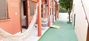 A corridor with a hammock, a green mat, and a door with a sign. - Pousada Semente (Porto Seguro)