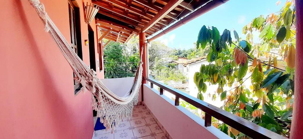 A balcony with a hammock, a view of greenery, and a building in the background.