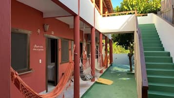 A covered outdoor area with a staircase, a hammock, and a door leading to an interior space.