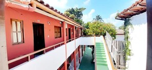 A red building with a balcony, a staircase, and a green pathway.