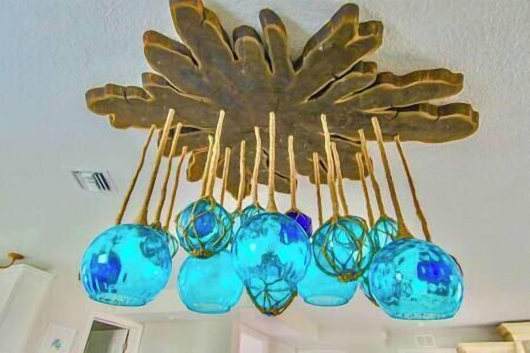 Een plafond met een decoratief metalen blad en hangende blauwe glazen versieringen.