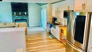 A modern kitchen with stainless steel appliances, a wooden floor, and white cabinetry.