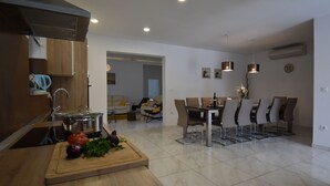 A modern kitchen with a wooden countertop, a dining area with a table and chairs, and a living space with a sofa and a coffee table.