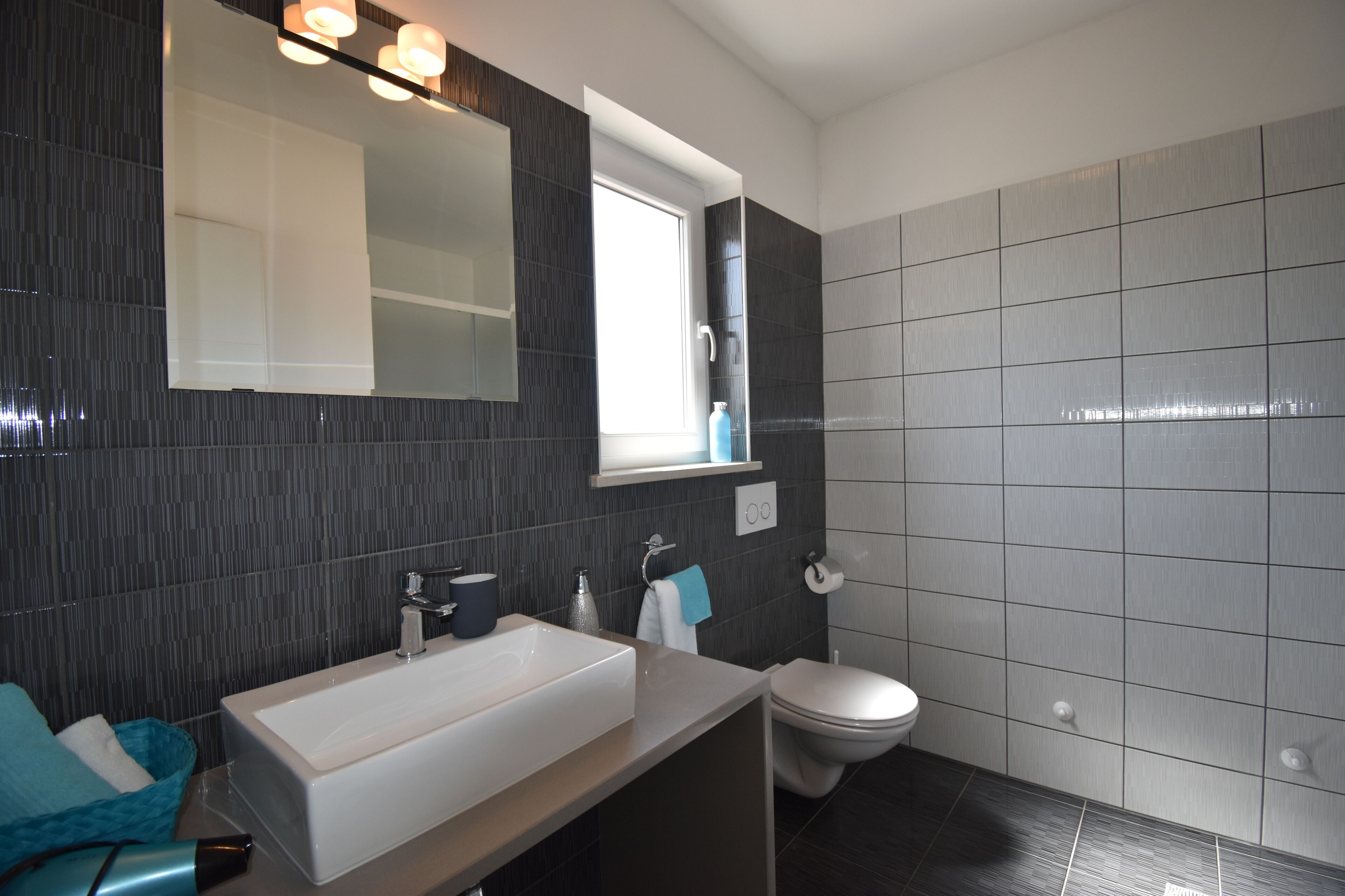 Ein modernes Badezimmer mit einem großen Waschbecken, einer Toilette und einem Spiegel.