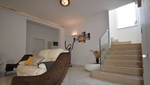 A modern living room with a sofa, a brown chair, and a staircase leading to an upper floor.