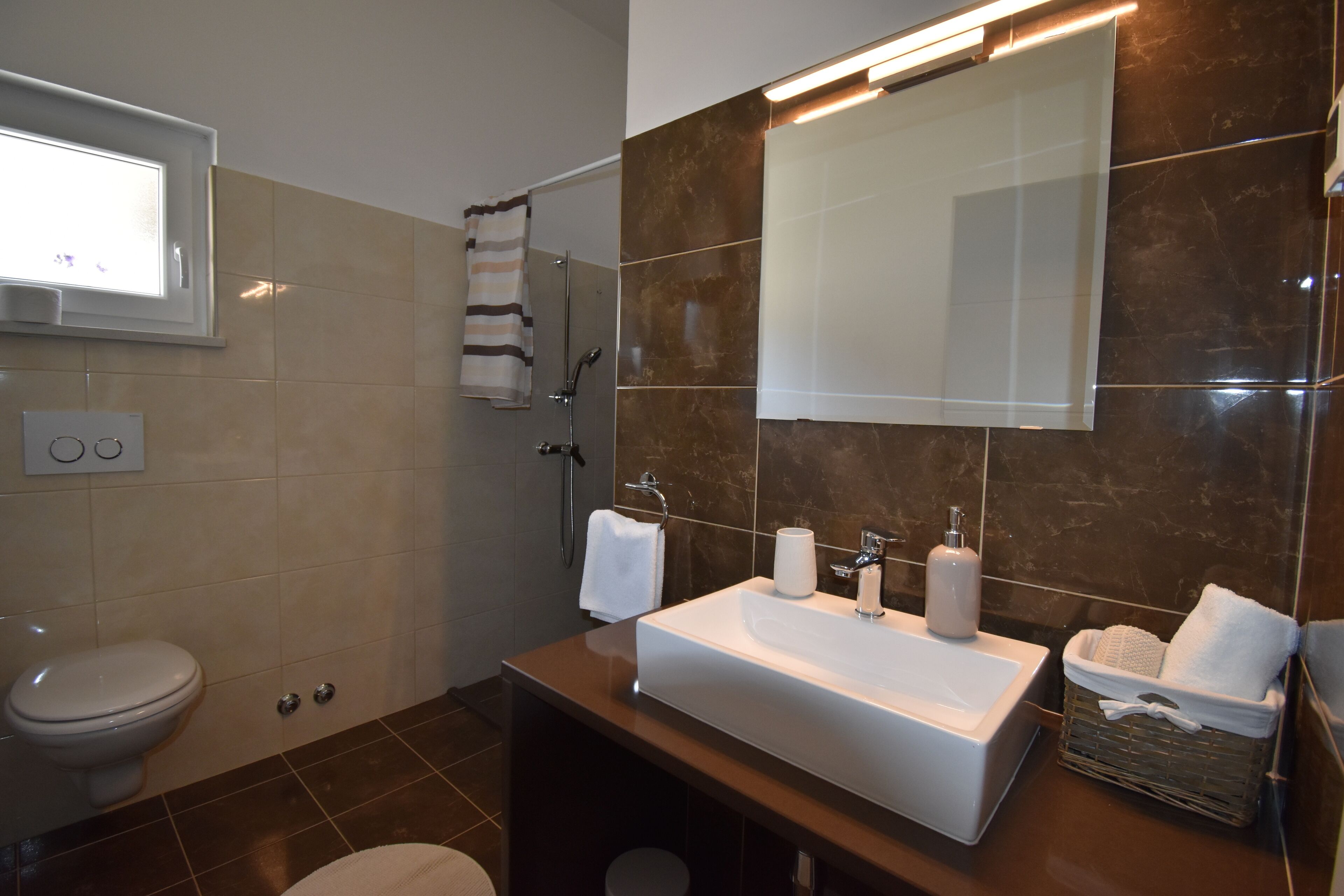 A modern bathroom with a large mirror, a white sink, and a shower area.