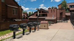 Ett bostadsområde med trähus, utomhusgrillar och en soptunna.