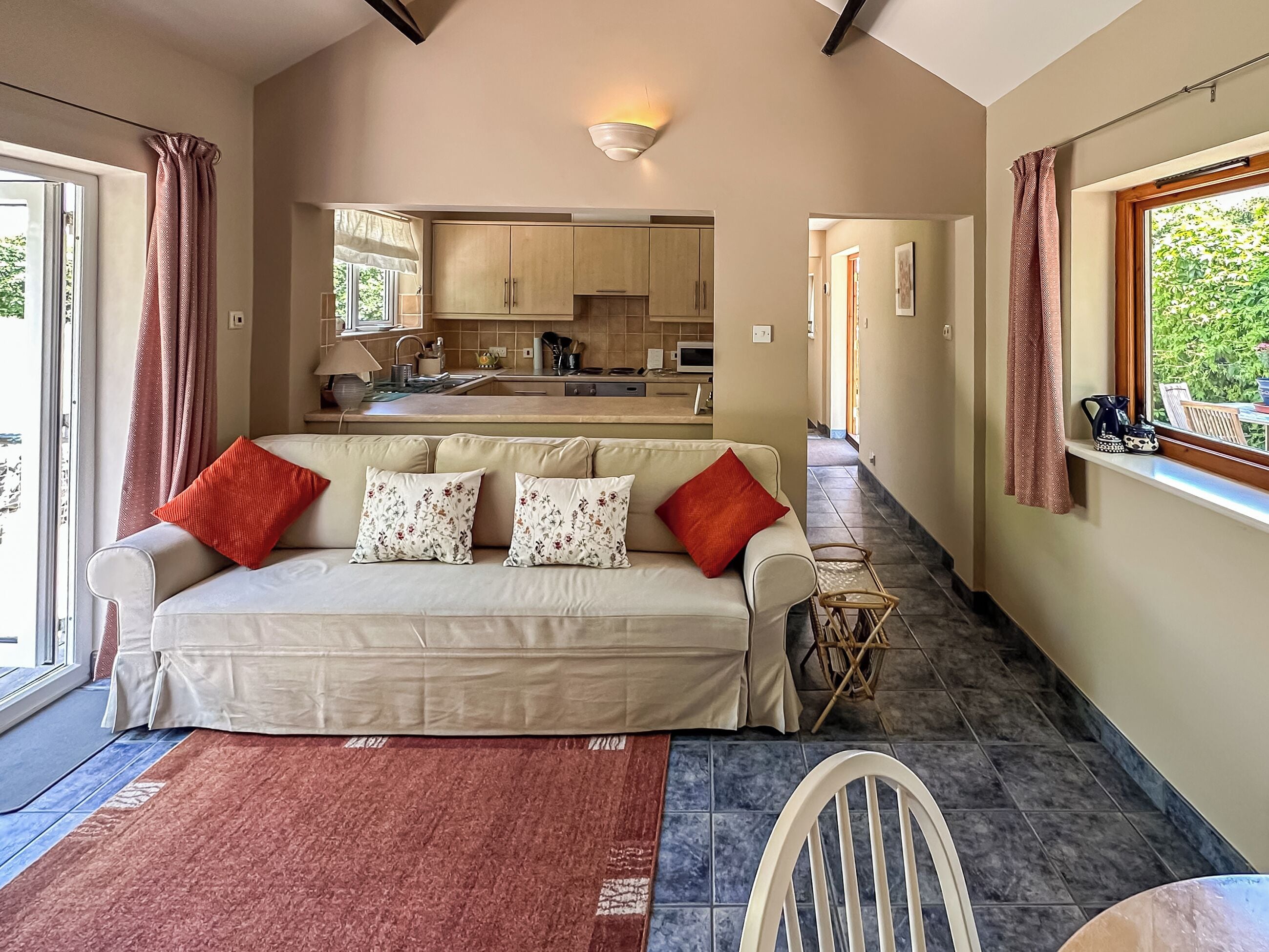 A spacious living area with a sofa, a dining table, and a kitchen in the background.