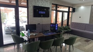 Una habitación con escritorio, sillas, televisor y sofá.